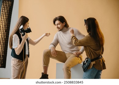 Behind the scenes of a photo shoot, a make-up artist and a photographer prepare the model for the photo shoot. - Powered by Shutterstock