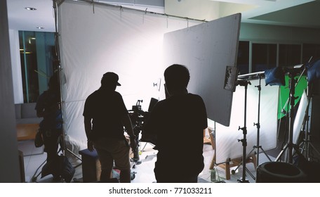 Behind The Scenes Of Shooting Video Or Movie Production Crew Team And Silhouette Of Camera And Equipment In Studio. 