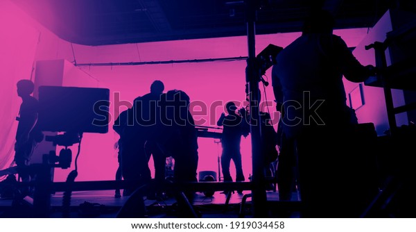 Behind the scenes of shooting video production\
and lighting set for filming movie which film crew team working in\
silhouette and professional equipment in studio for video. video\
production concept.