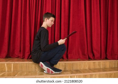 Behind the scenes of the theater, a young actor carefully studies his script. - Powered by Shutterstock