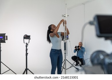 Behind the Scenes in Video Production Studio African American Working Setting Up Film and Lighting Equipment on Movie Set - Powered by Shutterstock