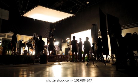 Behind The Scenes Of Video Shooting Production Crew Team Silhouette And Camera Equipment In Studio. 