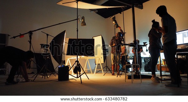 Behind the shooting production crew\
team and silhouette of camera and equipment in\
studio.