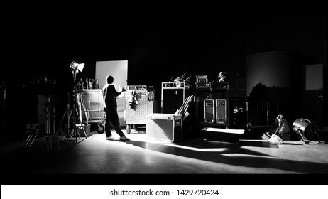 Behind The Shooting Of Video Online Commercial Production And Film Crew Team Working And Setting Light Or Camera Or Soft Box And Equipment Set Up In Big Studio In Silhouette Style