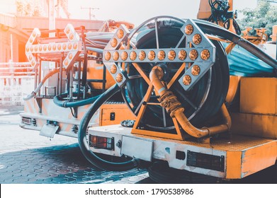 Behind The Toilet Pumping Service Car. Pump Water From The Sewage Canal During The Construction Of City Roads Truck With Orange Water Tank. 