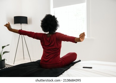 Behind View, Early Morning Routine Of Beautiful African Woman Stretching Arms Outwards While Sitting On Bed, With Copy Space