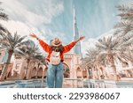 From behind, you can see the traveler girl arms spread wide as she take in the incredible view of the Burj Khalifa and the Dubai skyline.