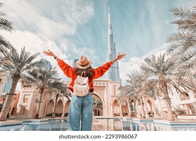 From behind, you can see the traveler girl arms spread wide as she take in the incredible view of the Burj Khalifa and the Dubai skyline.