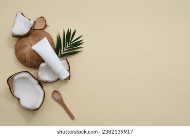 Beige background with fresh coconut and unlabeled cosmetic tube. Shower gel or lotion with Coconut extract will help retain water in the stratum corneum, leaving it feeling soft and smooth.