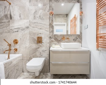 Beige Bathroom With Marble Style Tiles And Golden Taps, Lamps And Wall Heater