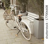 Beige bicycle with basket parked near the bench on the Amsterdam street