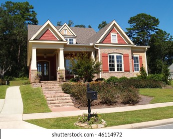 Beige Brick Home Having Peach And White Trim With Steps Leading Up To Squares Columns On The Porch.