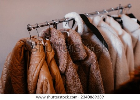 Beige brown women's clothes hanging on a hanger in a row. Autumn winter fashion collection set