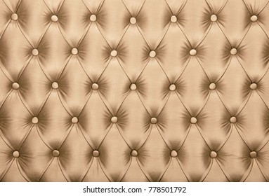 Beige capitone textile background, retro Chesterfield style checkered soft tufted fabric furniture diamond pattern decoration with buttons, close up