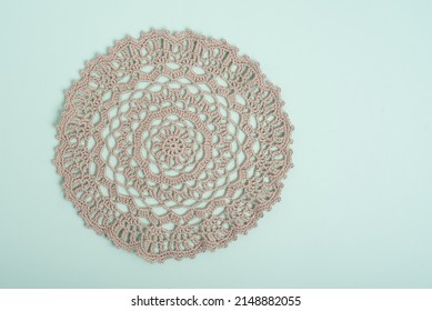 A beige crochet doily on a pale green background