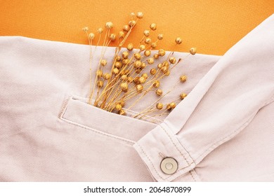 Beige denim shirt and linen flowers close-up, flat lay, to view. Natural durable linen fabrics concept. Comfortable casual clothing background. Fabrics made from recycled materials