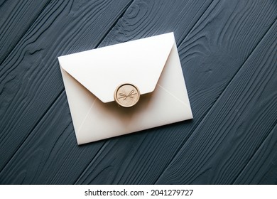 Beige envelope on a dark gray wooden table background. Invitation envelope for wedding, holiday, birthday, party invitation, Christmas envelope. Cose up photo.
