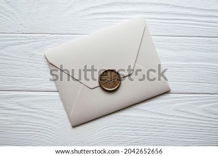 Beige envelope on a white wooden table background. Invitation envelope for wedding, holiday, birthday, party invitation, Christmas envelope. Cose up photo. Family tradition concept.