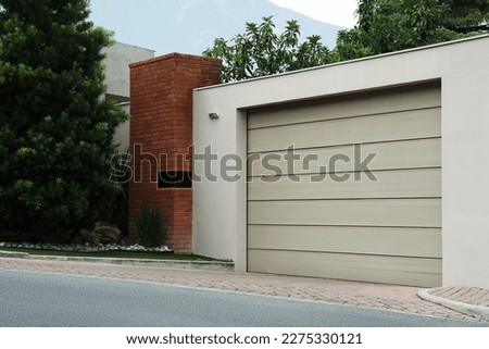 Beige garage with closed sectional door. Exterior design