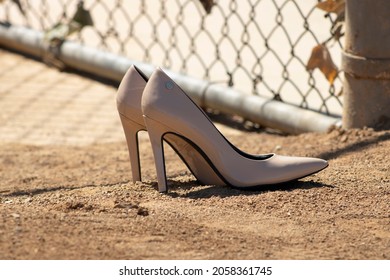 Beige high heels sitting on baseball field in sunlight 