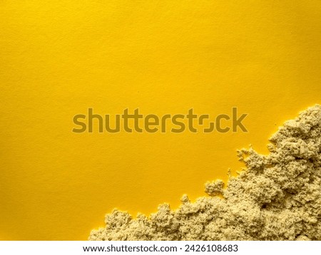 Beige kinetic sand for children on a yellow background, development and play at home with colorful sandbox molds, sculpting with sand 