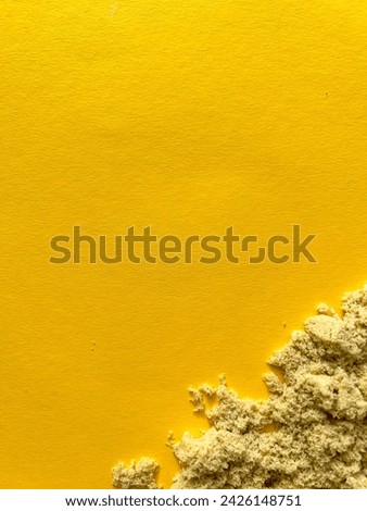 Beige kinetic sand for kids on yellow background, development and play at home with colorful sandbox molds, sand texture for background frame