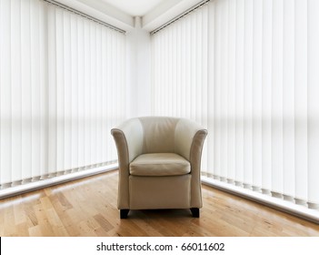 beige leather armchair in a room with wooden floor and vertical blinds