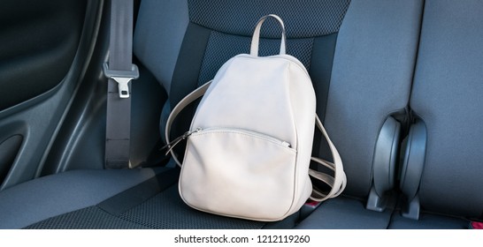 Beige leather backpack on a grey backseat of a car. - Shutterstock ID 1212119260