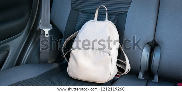 Beige\
leather backpack on a grey backseat of a\
car.