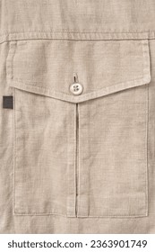 Beige linen fabric shirt flap patch pocket closeup as a background