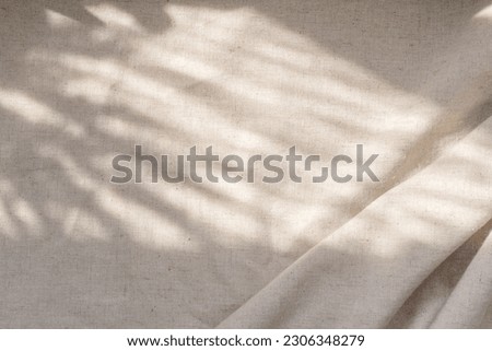 Beige linen fabric texture with folds and a natural floral sunlight shadows, aesthetic summer wedding bohemian background