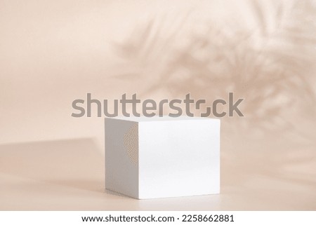 Beige pastel background for product presentation with shadow, tropical palm leaves and light. Podium, stage pedestal platform for cosmetic product. Empty square podium. Mockup.