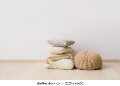 Beige pouf and cushions near light wall