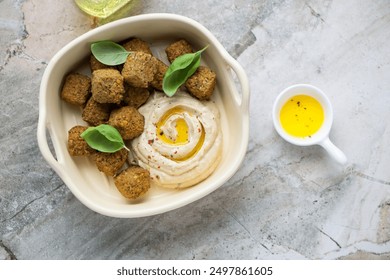 Beige serving tray with hummus and falafel on a grey granite background, horizontal shot, above view