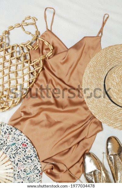Beige silk slip dress with accessory, top\
view. Simple elegant summer\
outfit.	\
