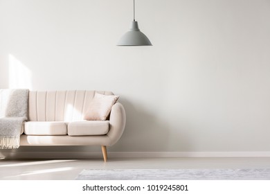 Beige Sofa Against White, Empty Wall With Copy Space In Simple Living Room Interior With Lamp