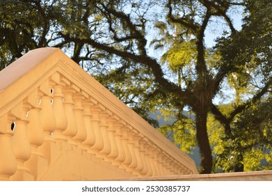 Beige stone balustrade under sunlight with tree canopy in background - Powered by Shutterstock