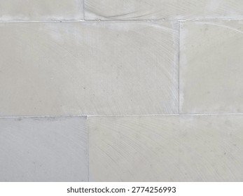 Beige stone wall texture serving as a neutral background with subtle tile seams and plastered surface. Minimal architectural detail creates a calm, modern backdrop for design, editorial, and construction use