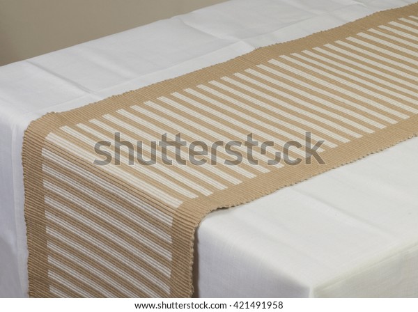 Beige striped\
dining table runner on white\
cover