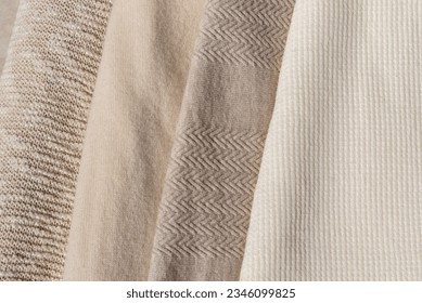 Beige, taupe, light brown, creamy wool, cotton and cashmere blend knitted sweaters texture stack together, warm neutral color autumn clothes, knitwear wardrobe concept