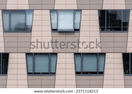 Beige wall of a modern building with trapezoidal windows. From the Windows of the world series. Foto stock © 