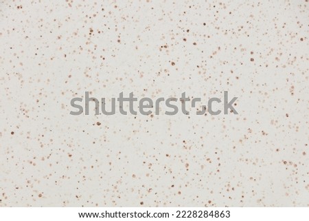 Beige and white ceramic texture of plate with brown dots.