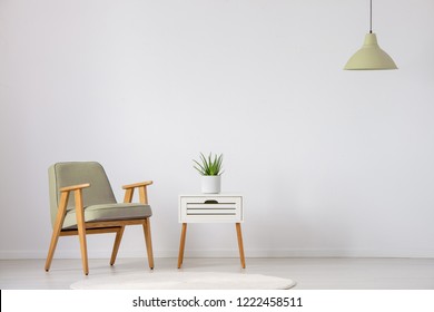 Beiger Holzsessel neben dem Schrank mit Pflanzen im flachen Inneren mit Lampe und Kopienraum. Real Foto
