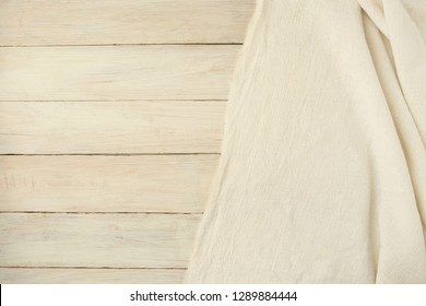 Beige Woven Textile Drape On Wooden  Background. Waving Cloth Fabric Canvas On White Planking With Empty Place.
