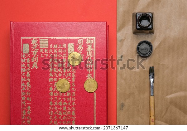 Beijing, China, 08-11-21: I Ching ancient\
Chinese oracle, Book of Changes or Classic of Changes with old\
coins, ink and brush on a red\
background
