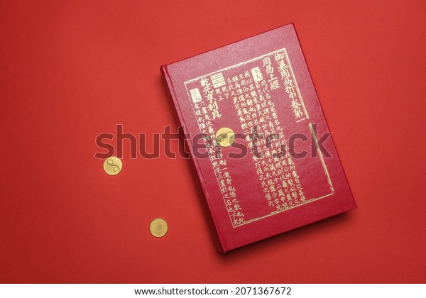Beijing, China, 08-11-21: I ching ancient\
Chinese oracle, Book of Changes or Classic of Changes with old\
coins on a red\
background