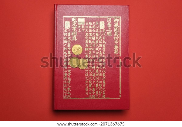 Beijing, China, 08-11-21: I ching ancient\
Chinese oracle, Book of Changes or Classic of Changes with old\
coins on a red\
background