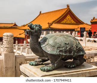 Beijing, China - April 20, 2017 - Bronze turtle sculpture outside the Hall of Supreme Harmony in the  Forbidden City. Behind it white marble balustrades and yellow glazed roofs can be seen.