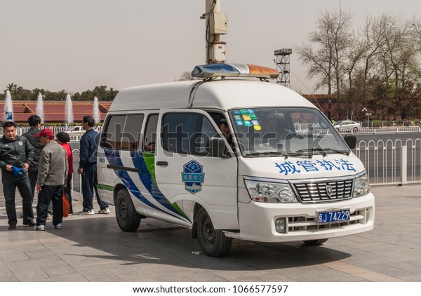 Beijing,\
China - April 27, 2010: White and blue police van parked on side of\
Tienanmen Square. Officers inside and outside.\
