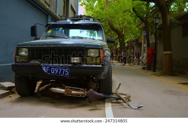 BEIJING, CHINA, AUGUST 20, 2013:\
bicycle run over by a jeep inside of the hutong area of\
beijing